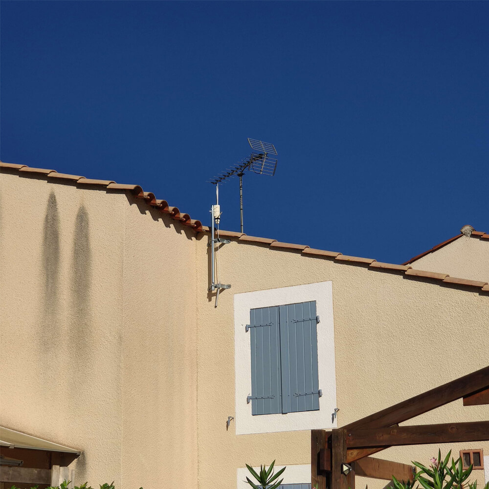 Antenne Wi-Fi fixée sur un mât à l'extérieur d'une maison.
